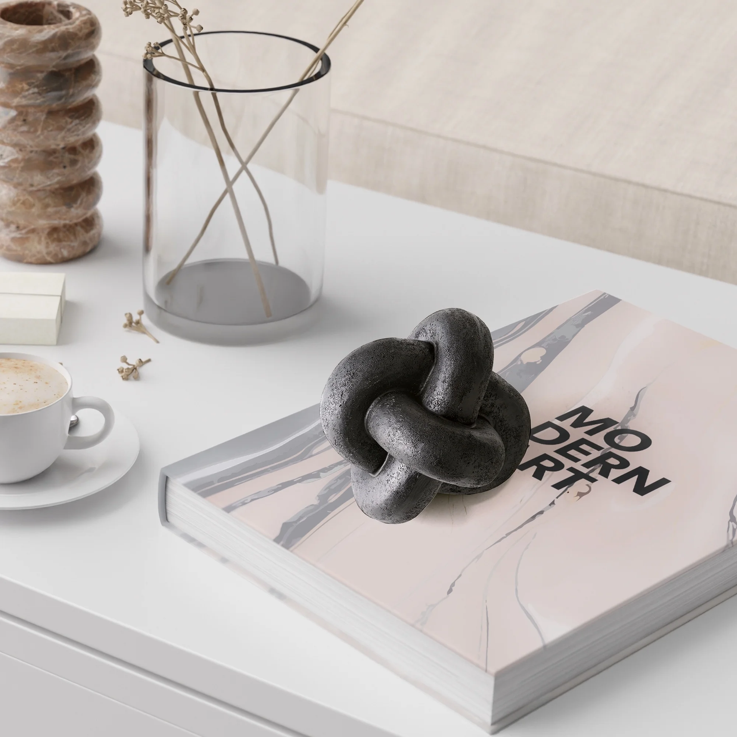 Decorative knot on a book with a cup of coffee and vase in the background