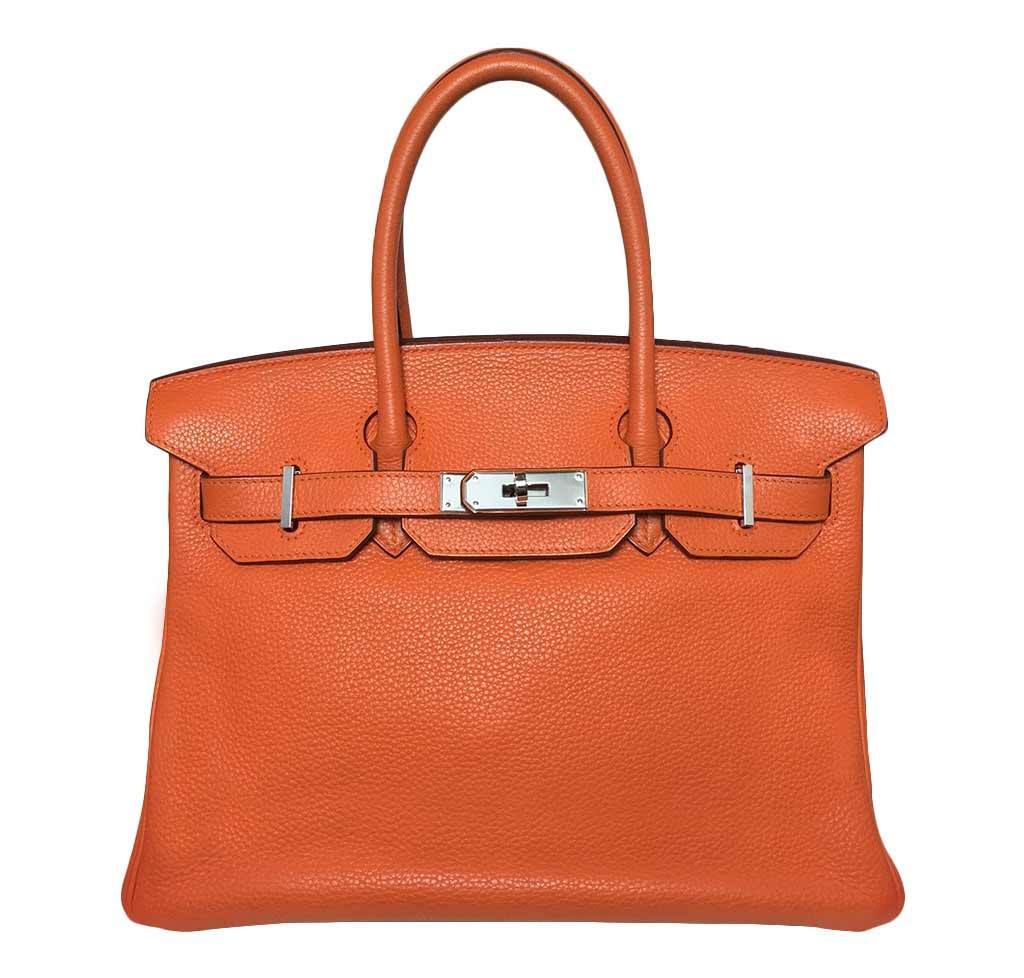 Orange leather handbag with silver hardware on a white background