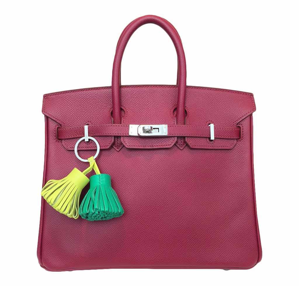 Pink handbag with colorful tassel keychain on a white background