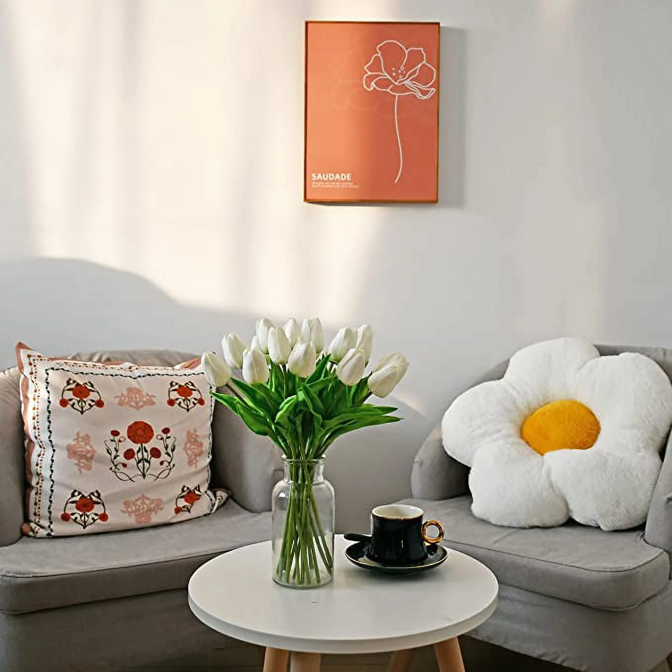 Living room with a gray sofa, decorative pillows, a vase of white tulips, and a framed artwork on the wall.
