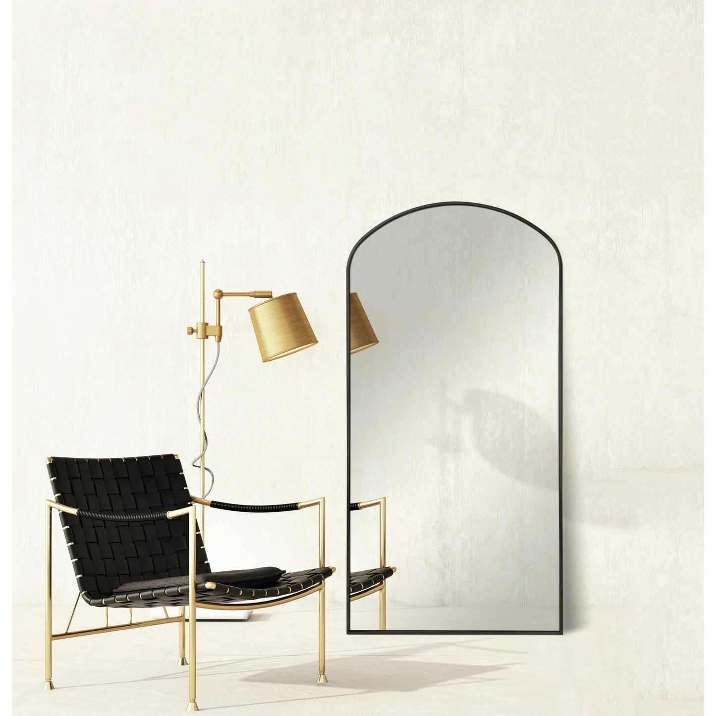 Modern black chair with gold frame next to a tall mirror on a white wall.