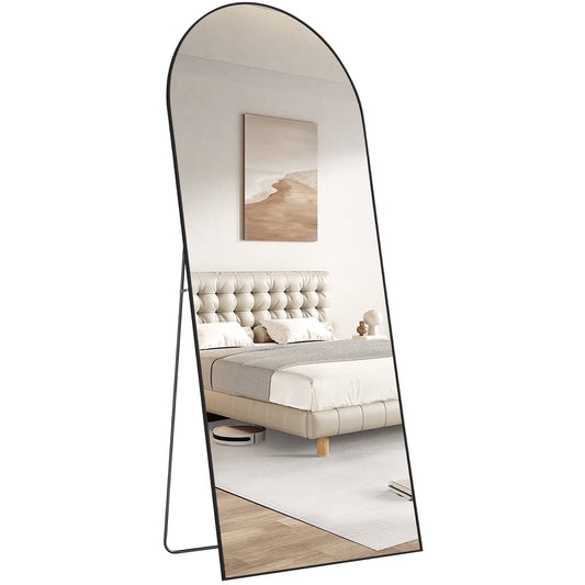 Full-length mirror reflecting a bedroom with a bed and decor.