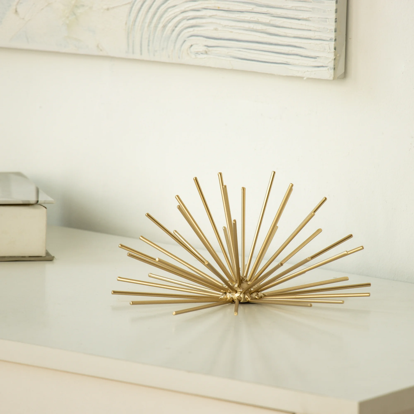 Decorative gold wall sculpture on a white surface with a neutral background