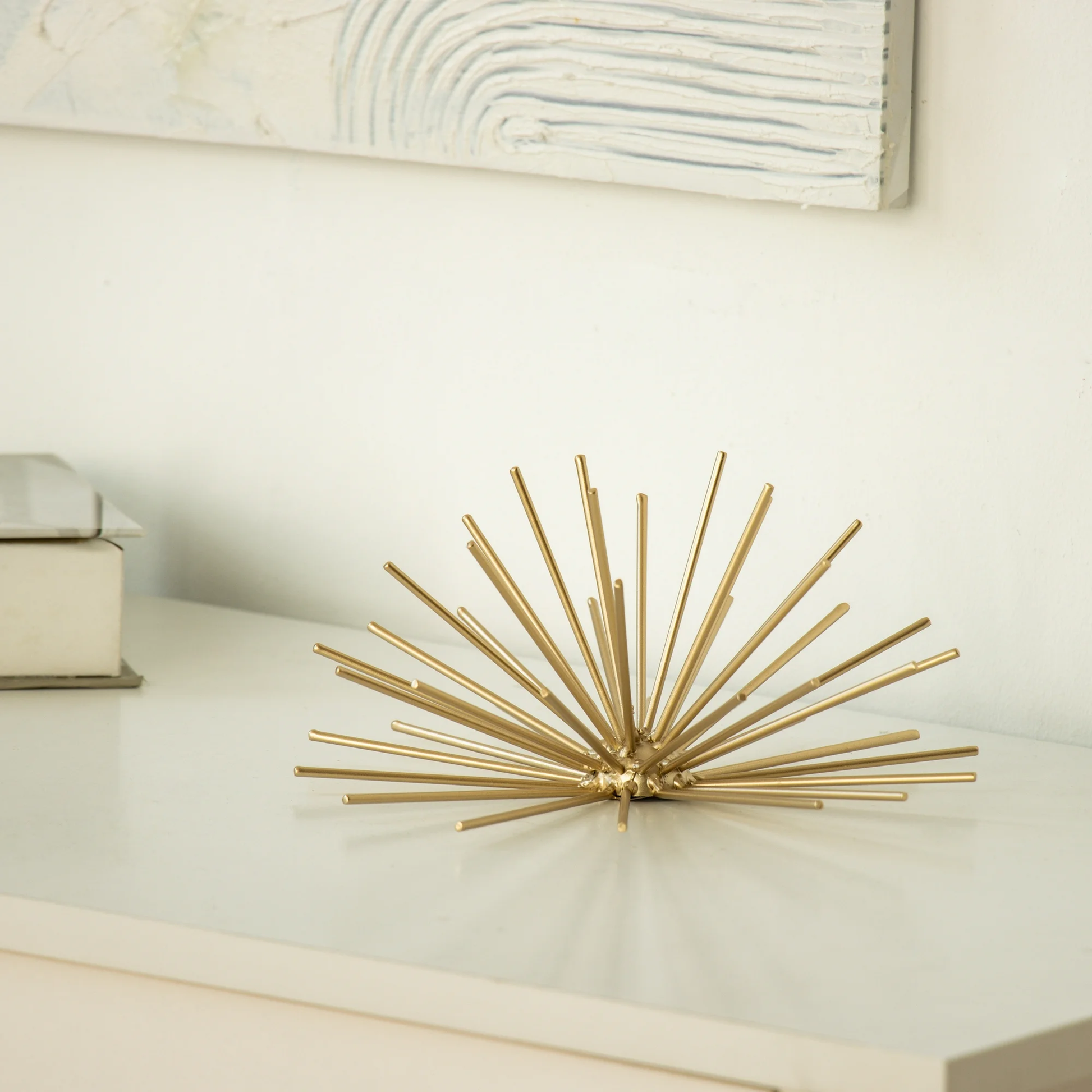 Decorative gold wall sculpture on a white surface with a neutral background