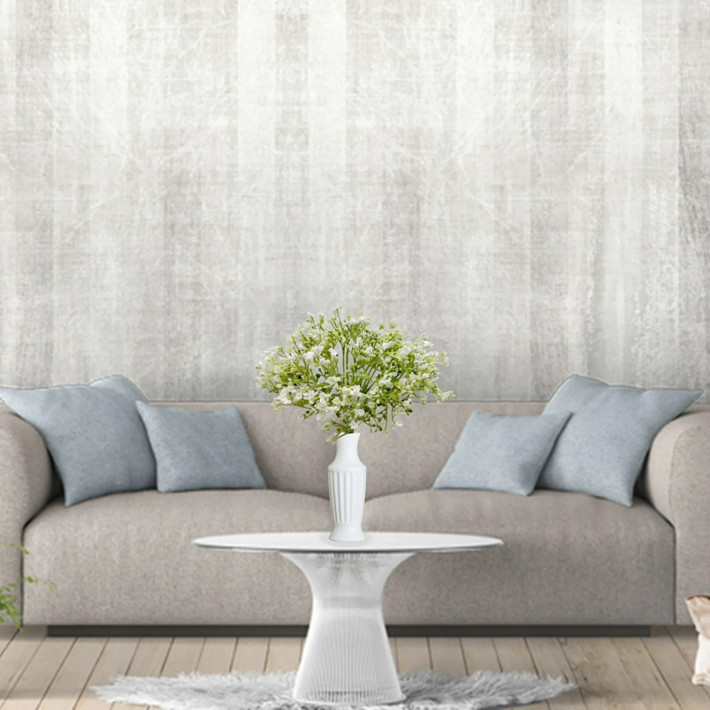 Modern living room with a gray sofa, white coffee table, and decorative plant against a textured wall.