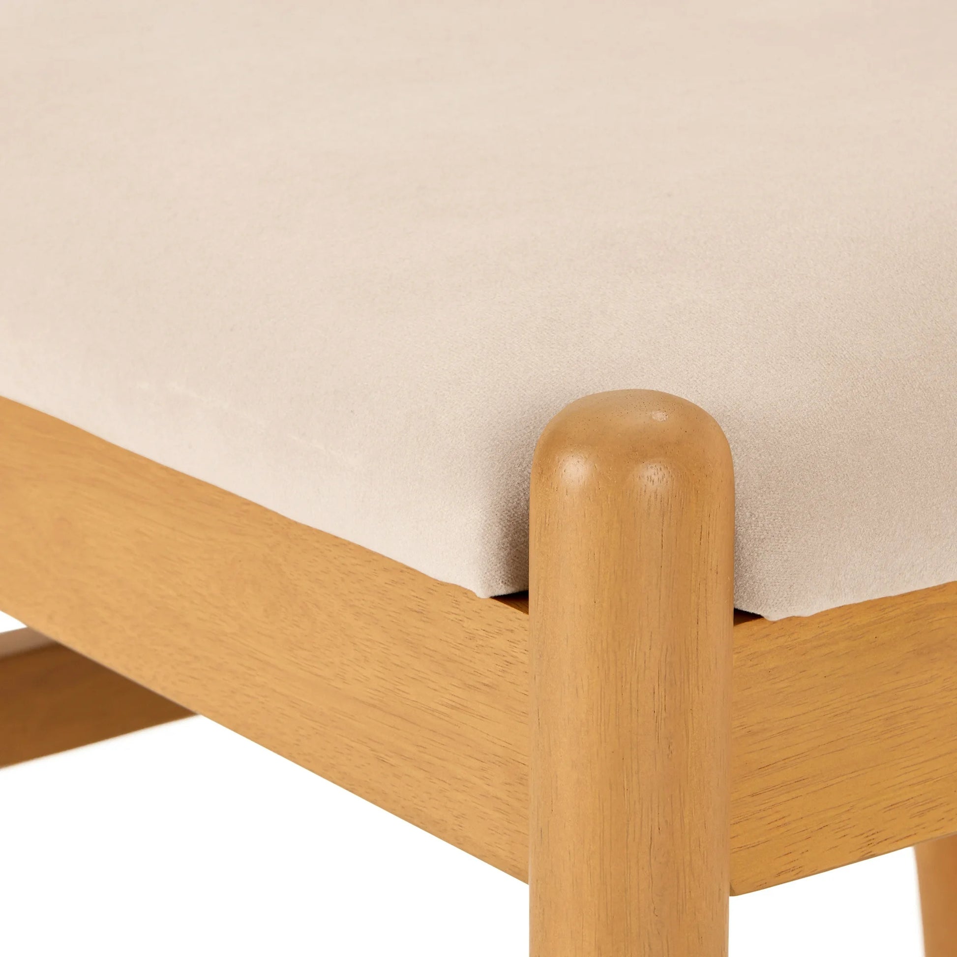 Wooden bed frame corner with beige mattress against a plain background